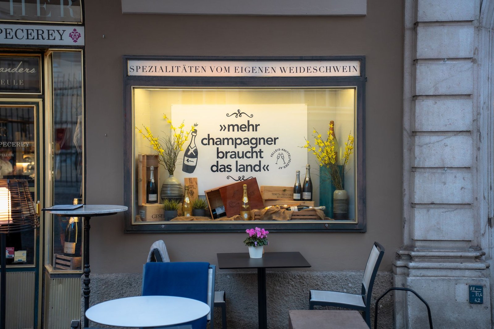 Charming shop window display in Salzburg featuring champagne and flowers.